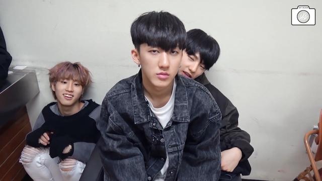 Sulky Changbin sits on Hyunjin's lap. Han crouches low next to them, and looks a bit spacey.