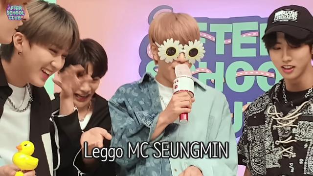 Seungmin rapping while wearing novelty glasses shaped like daisies. Lee Know, Changbin, I.N and Han are enjoying his performance