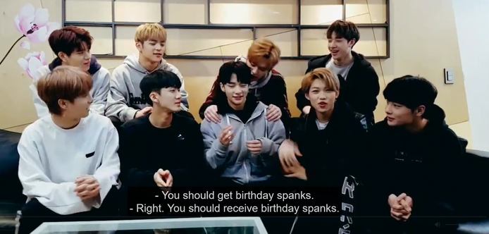 skz members during a livestream. Lee Know sits behind Hyunjin with his hands on Hyunjin's shoulders and his mouth near Hyunjin's ear.
