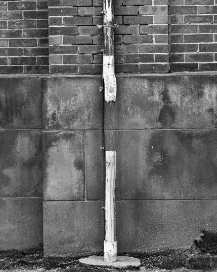 A drain pipe with a missing section, captured in monochrome