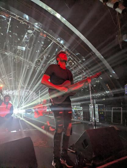Guitarist during a solo, white starry lights coming from the back