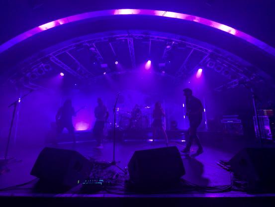 Entire band on stage, silhouetted in purple lights