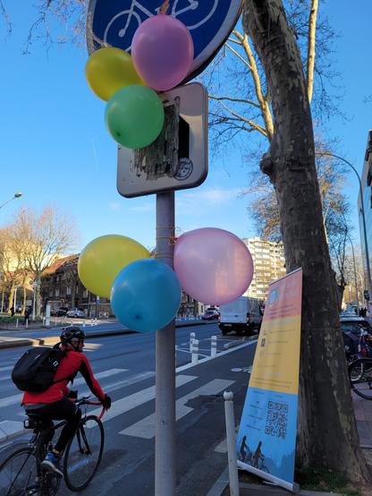 Cycliste sur la nouvelle piste cyclable. Ballons accrochés sur un panneau vélo
