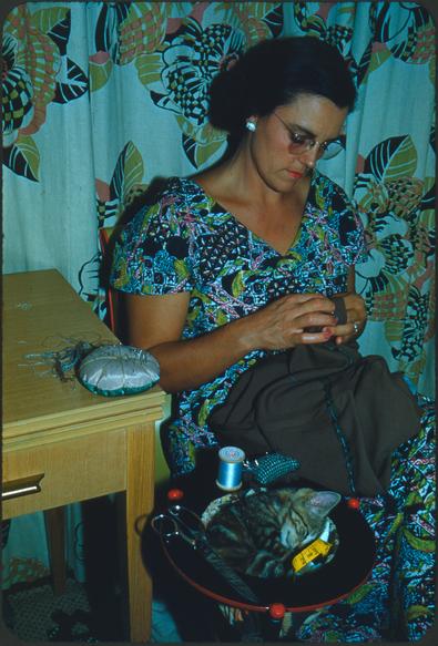 1952 "Misty in the sewing kit" A woman sewing with a kitten curled up in a basket