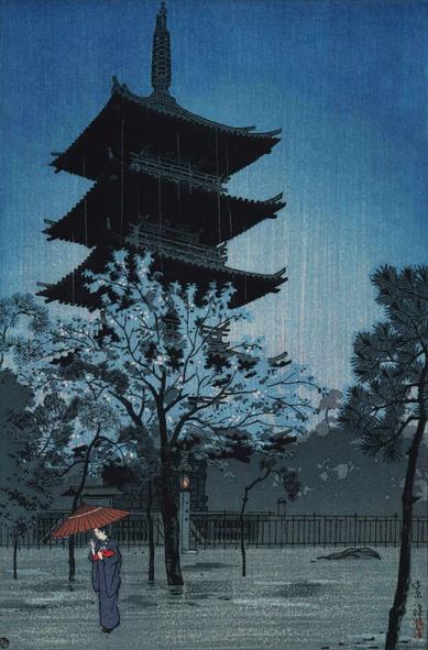 A spring rain falls at Hokan-ji Temple in Kyoto. A single female figure carries a bamboo umbrella in one hand and a small wrapped package in the other as she crosses the temple grounds; on her way, she passes beneath a cherry tree in full bloom. In the background, the famous five-story Yasaka Pagoda stands tall against the gloomy overcast sky.