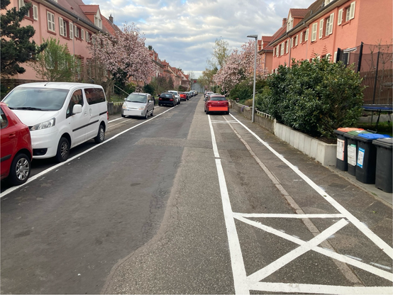 Foto der Karlsruher Anwohnerstraße Gustav-Binz-Straße im Stadtteil Nordstadt. Die schmale Straße hat zwei Gehwege, und eine Fahrbahn. Beide Gewege sind so mit Autos zugeparkt, dass kein Passieren möglich ist. Eine neu aufgetragene Markierung legalisiert das Verhalten.