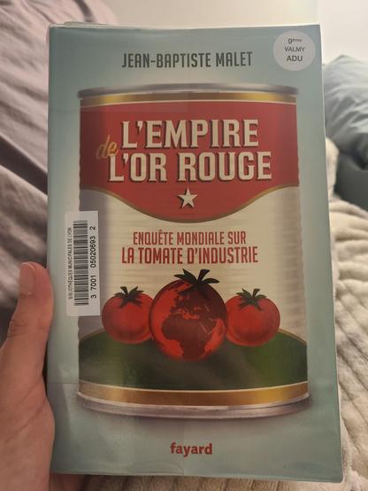 Photo de la couverture du livre "L'empire de l'or rouge, enquête mondiale sur la tomate d'industrie", de Jean-Baptiste Malet, aux éditions Fayard. La couverture est bleu pâle, et le titre est écrit sur une boîte de conserve aux couleurs rouge, blanc et vert, avec 3 tomates dessinées en bas de la boîte. On peut voir l'Europe, l'essentiel de l'Afrique et du Moyen-Orient sur la tomate du milieu.