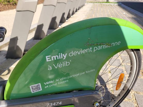 Roue arrière d'un velib vert mécanique où on peut lire "Emily devient parisienne à Vélib'"
