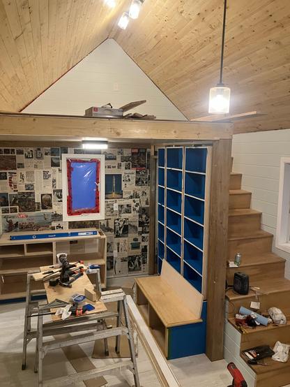 Interior view of the cabin. Looking at the loft, stairs, built in shelving and bench, and feature wall.
