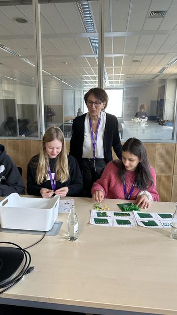 Staatssekretärin Dr. Ute Leidig schaut interessiert zu, wie zwei Mädchen Aufgaben beim Girls'Day bei Siemens Energy Global GmbH & Co. KG. lösen.