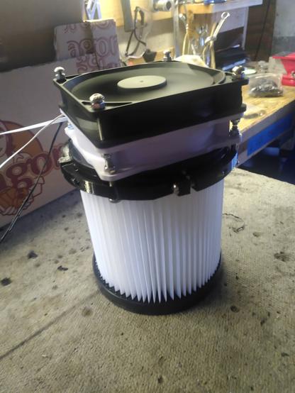 Un purificateur maison, avec deux ventilateurs d'ordinateur sur le dessus. En dessous il y a un filtre d'aspirateur cylindrique, qui est attaché aux ventilateurs via quatre pièces en quart