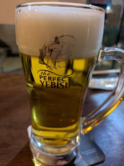 A mug of beer with, if I'm being honest, a bit too much head on it. The mug reads "The Perfect Yebisu"