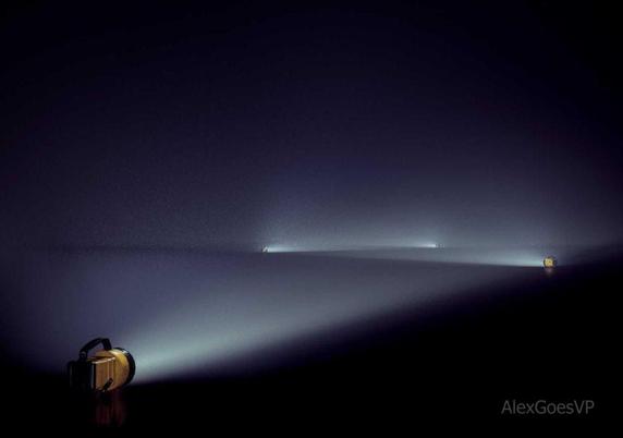 Portable lights laying on a dark floor and casting their light in the dark. They are arranged in a zig zag pattern.