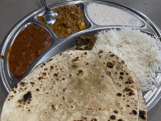 Metal plate with 4 sections holding 2 curries, raita, rice and pickle. Roti sit on top. Tiny amount of pickle, even after I asked for it. I had to ask for more.