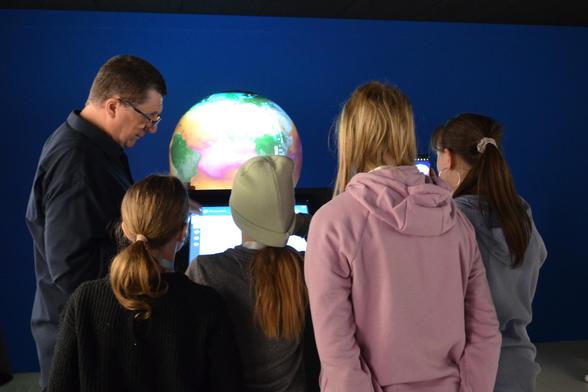 Michael Böttinger from DKRZ is showing four students how to operate a globe that visualizes different climate simulations.