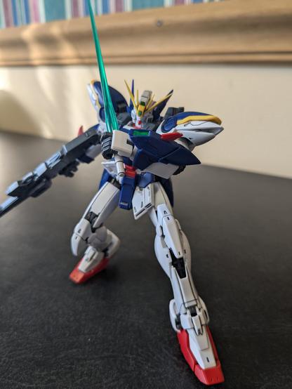 RG Wing Gundam without wings preparing to slice the viewer with its green beam saber while holding a rifle in its off hand