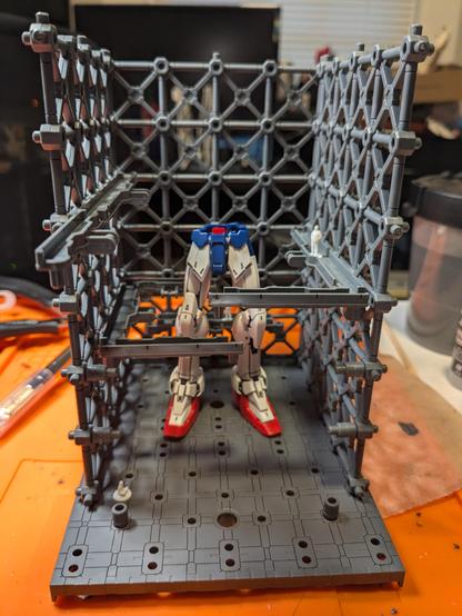 The legs and waist of the RG Wing Gundam EW standing in the 30MM Truss Base repair station with 1/144 scale 3D printed technicians