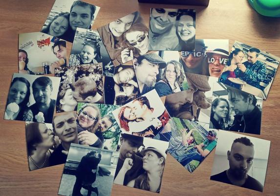 20 plus 4x4 square photo prints are laid out atop a honey-gold desk. The people in the photos are a man, a woman. Sometimes, they pose together or with a pet. Sometimes it's only one of them in the photo. Several of the photos are black and white or sepia while others are in color.