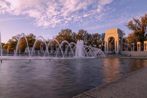 Serene view of the World War II Memorial fountain at sunset, highlighting the Atlantic arch and tranquil reflections in Washington D.C.