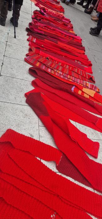 Detalj av en enormt lång röd halsduk (1,5 km) som ligger utlagd i veck på Sergels torg våren 2024.
