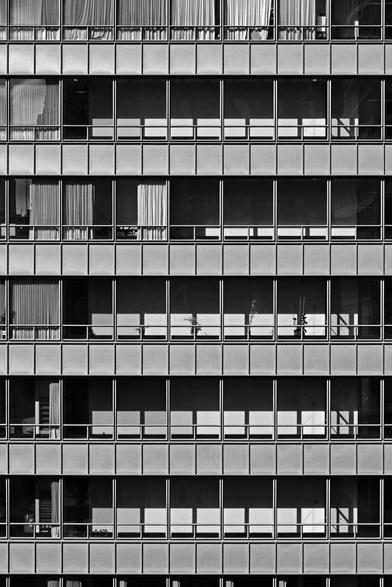 Black and white photo of a brightly lit section of the façade of a steel and glass skyscraper