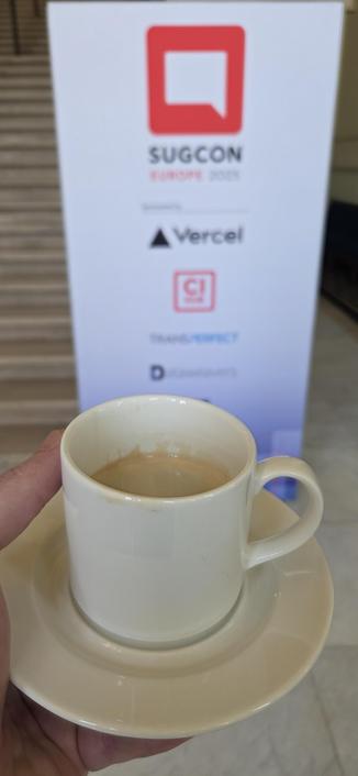 A cup of coffee in front of the SUGCON EU 2025 banner