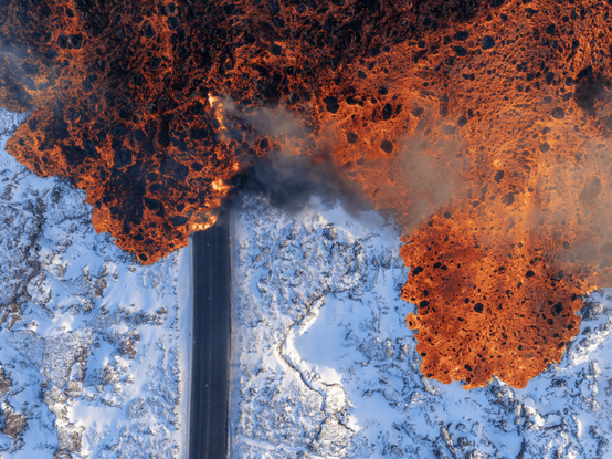 Aerial view of lava overflowing a road and the surrounding landscape in Iceland.