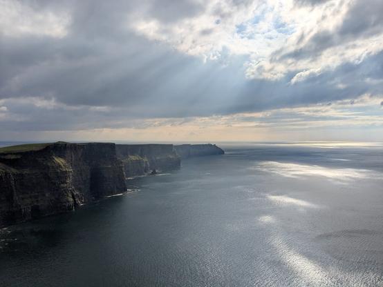 View of the Moher Cliffs. 
Vertical Cliffs, stretching out into the Atlantic. Broken sun and the beginnings of a sunset