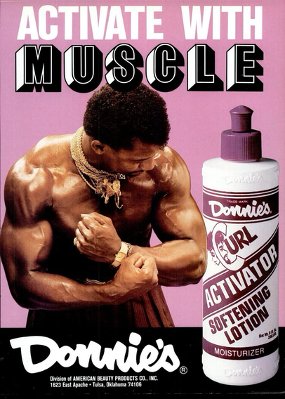 A bodybuilder shows off his muscles next to a bottle of the curl activator. He’s got a lot of gold jewelry.