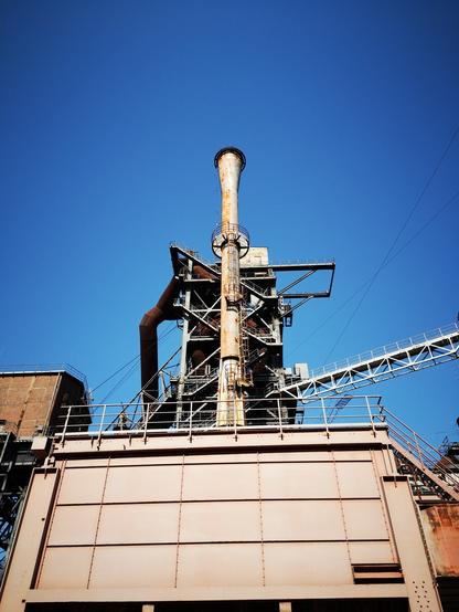 Unter blauem Himmel Relikte stillgelegter Industrie. Schornstein, Rohre, Gebäude.