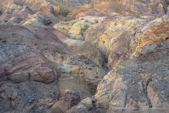 An intimate landscape photo showing a rugged desert landscape with a deep canyon in the soft evening light past sunset. No sky is visible in the frame, and the deep canyon eludes the viewer from seeing its bottom.
