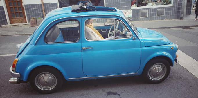 a sky blue original Fiat 500 waiting at a light