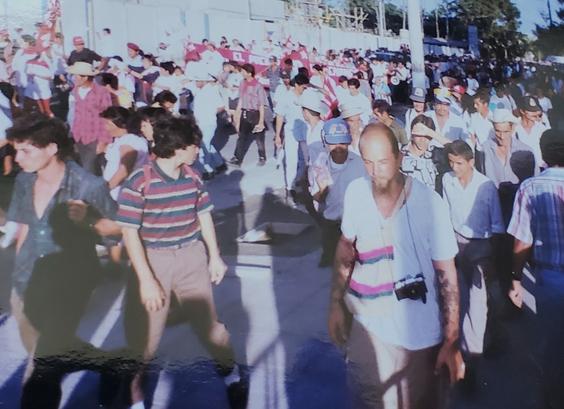 My friend, Shannon, marching in an anti-death squad demonstration in San Salvador, 1993. Lots of read and white FMLN flags and banners.