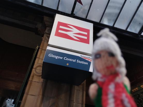 Puppet in front of Glasgow Central Station signage.