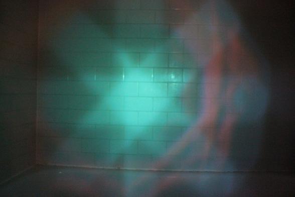 Mysterious reflection on walls of dark bathtub. Expanding central orb.
