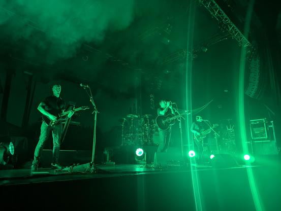 Three band members in harsh green stage lights