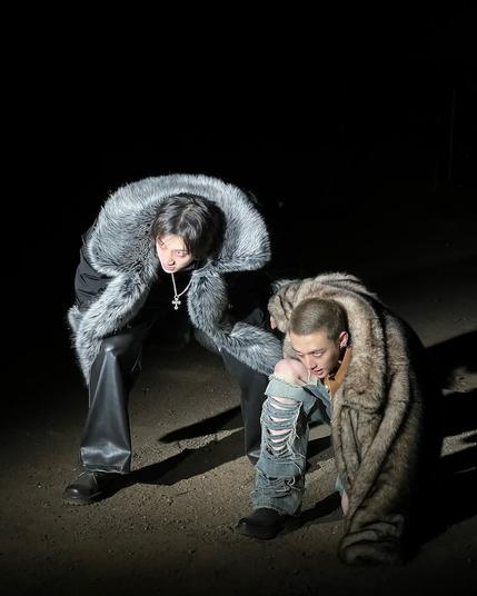 Bang Chan and Hyunjin during filming of the Escape MV. Both are wearing fur(?) coats, crouched down and staring at something off-screen that is probably a threat