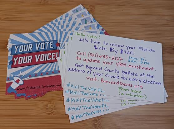 Photo of 10 Postcards To Voters. 5 stamped postcards are arranged in a fan and placed front side up, showing a red-white-and-blue "YOUR VOTE YOUR VOICE!" design with "www.PostcardsToVoters.org" handwritten across the bottom.

Covering up the recipient address are 5 postcards arranged in a fan, showing the back of the card with the following handwritten message in different colors:

"Hello Voter!
It's time to renew your Florida Vote By Mail.
Call (321) 633-2127 Mon. - Fri. 8 AM - 5 PM to update your VBM enrollment.
Get Brevard County ballots at the address of your choice for every election.
Visit: BrevardDems.org 
#MailTheVoteFL
From Irene
(a volunteer)"