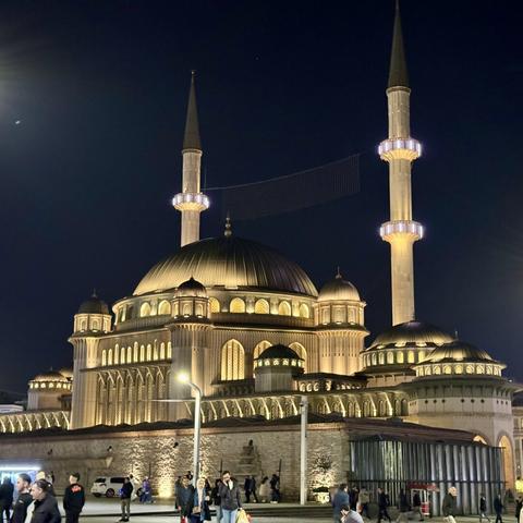 Taksim mosque at night, a huge mosque lit beautifully in yellow with a black sky behind it