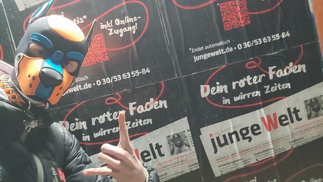 Aki vor Plakatwerbung für die junge Welt