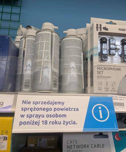 Zdjęcie półki sklepowej w Action, na której stoją puszki że sprężonym powietrzem, a pod nimi plakietka z napisem "Nie sprzedajemy sprężonego powietrza w sprayu osobom poniżej 18 roku życia."