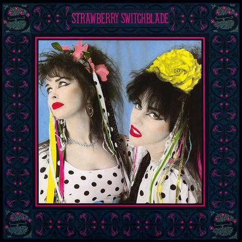 The cover of Strawberry Switchblade's album - two women in polka dot dresses, wearing hairbands of plastic flowers with coloured and polka dot ribbons trailing. The photo has been colourised to emphasise the flowers and their lipstick. The picture has a border of a stylised dark floral design with the band's name at the top in deep pink.
