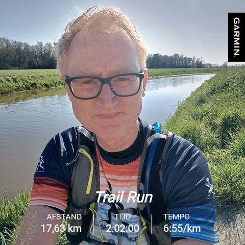 Selfie of runner alongside a canal surrounded by grasslands. A tree line on the left, beautiful weather, blue sky.