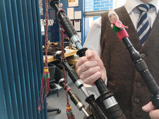 Finger puppet tries the bagpipes.