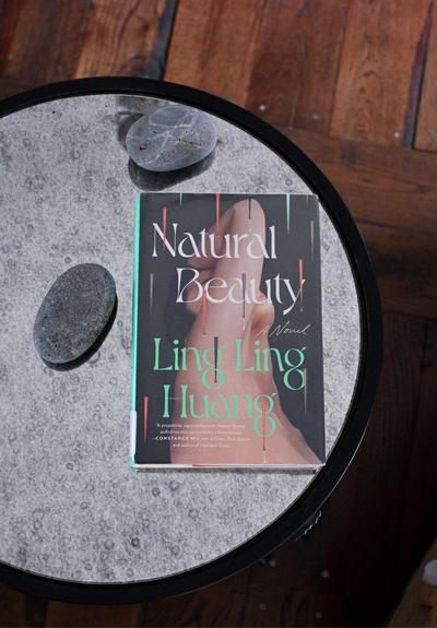 Overlay. Book, Natural Beauty by Ling Ling Huang, set on mirrored table. Adorned with two gray stones.