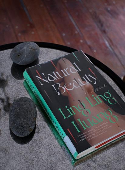 Book, Natural Beauty by Ling Ling Huang, set on mirrored table. Adorned with two gray stones.