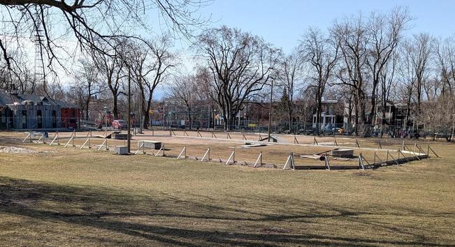 An outdoor skating rink with hockey boards being disassembled for the season, located in our local park.