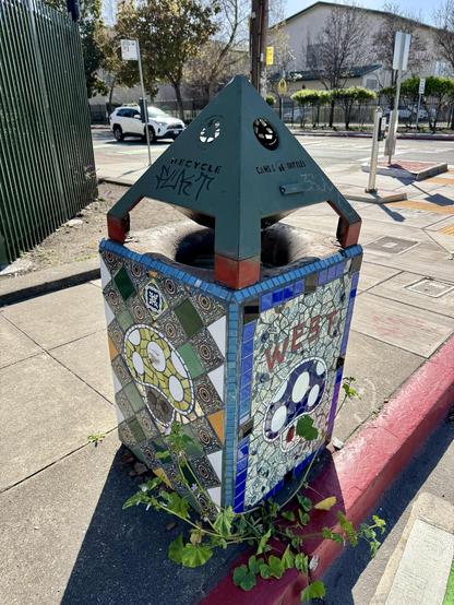 A view of the trash can from the other side, so you can also see the green-topped mushroom mosaic art.
