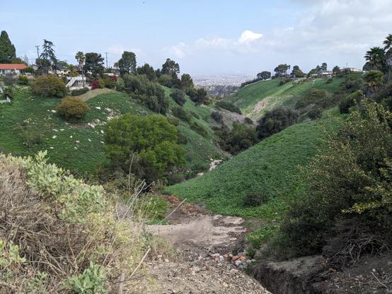 Looking along a narrow valley between rolling green hills fitted with trees and a few houses