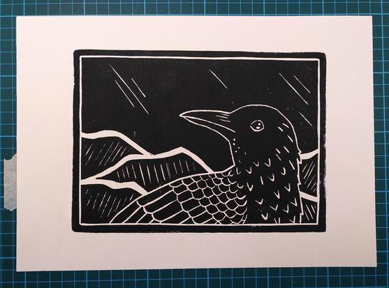 Linocut print of a crow turning it's head slightly upwards. The sky is dark and there are hills in the background.